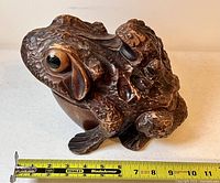 Side view of carved wooden frog box showing length against a measuring tape