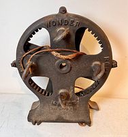 Front view of antique cast iron rope maker tool showing 'WONDER ROPER' marking and attached rope.