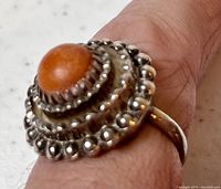 Top view showing the round Baltic amber cabochon set in an ornate silver bezel with beaded and scalloped detailing.