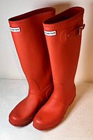 Pair of red Hunter rain boots with buckle detail, front angled view