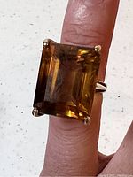 Front view of emerald-cut smokey topaz quartz ring shown on finger