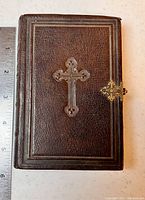 Front of the antique German Bible showing embossed cross and metal lock clasp.