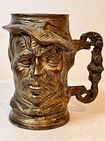 Front view of brass face stein showing facial features and spout