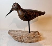 Side view of a hand carved wooden Dowitcher bird decoy mounted on driftwood base