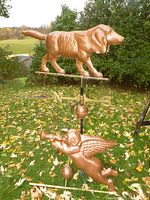Both copper weathervane toppers mounted on rod with directional letters in background of lawn and trees