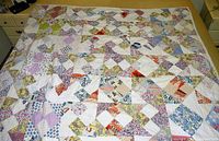 Top view of the full quilt spread on a bed, showing its complete patchwork pattern and size.
