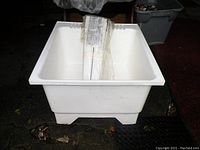 White plastic laundry tub front view showing overall shape and condition with some dirt on surface.