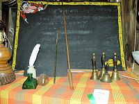 Front view of entire lot featuring chalkboard, bells, inkwells, quill, and pointers on cloth surface.