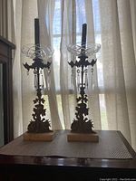Two antique brass and marble candlesticks with crystal bobeches and hanging crystal drops, showing the full height and details of each