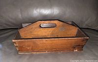 Side view of antique wooden letter caddy showing dovetail joints and wood grain.