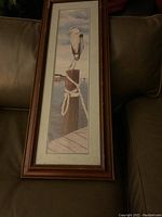 Framed print showing full artwork of blue heron perched on dock post with water background