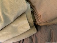 Close-up photo of folded sage green velvet curtain panels and gold curtain panels showing fabric texture and colors.