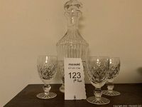 Front view of Waterford decanter and four cordial glasses arranged behind a label.