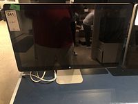 Front view of monitor powered off, showing black bezel, silver stand, reflective screen.