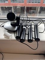 Camera on base with four handheld microphones and power cable visible on windowsill