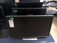 Three Dell 24-inch flat panel monitors stacked on a table, showing front view of each monitor with visible Dell logo and stands.