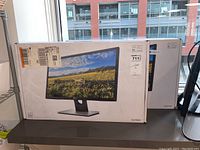 Two boxed Dell monitors on shelf by window.