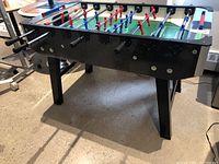 Side view of table showing black laminate finish, legs and rod handles.