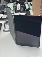 Apple iPad Model A1474 standing with gray smart cover partially open.