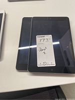 Two Apple iPads stacked on a desk, front screen visible with a label reading 'iPad 2'.
