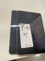 Two black Apple iPads stacked, front visible with a MaxSold sticker showing 'iPad 2' handwritten