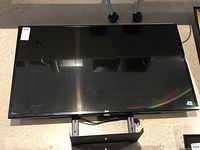 Front view of LG flatscreen TV showing black glossy screen and attached stand
