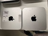 Two Mac mini units side by side showing top surfaces and Apple logos.
