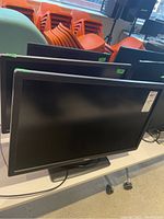 Three monitors displayed on a table, two large similar 27-inch Dell monitors in front and one smaller 21-inch monitor behind them.