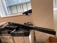 Long black rack PDU with yellow-labeled outlets atop UPS units