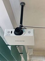 Projector body mounted on ceiling with mounting pole and cables