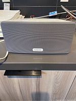 Front view of white Sonos Play:3 speaker on countertop showing metal grille and logo