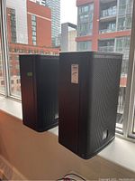 Two speakers angled side by side on windowsill, showing overall condition