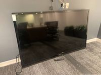 Front view of TV leaning against wall with remote on floor