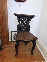 Front view of the vintage carved wooden side chair showcasing the sculpted back and basket-weave patterned seat.