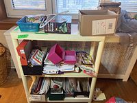 Wide view showing small shelf with various items including blue basket with costume jewellery, boxes with cards, and Electric Putting Partner box.