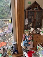 Wide shot showing display case next to window, with doll and candle holders/vases visible.