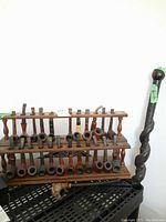 Two-tier wooden rack filled with briar pipes and carved pipe at front