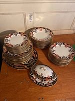 Stacked dinner plates, salad plates, bowls and covered gravy boat on wooden surface