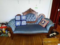 Full view of vintage wood frame settee with blue upholstery, showing both cushions on settee