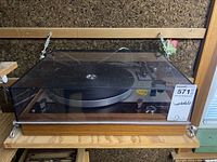 Front view of turntable with closed acrylic dust cover on wood plinth