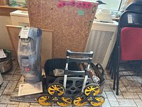 Hoover FloorMate hard floor cleaner, Upcart foldable dolly, two cork boards, and bag of electrical accessories shown together on floor.