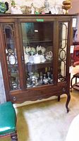 Front view of the wood china cabinet showing glass door and wood frame.