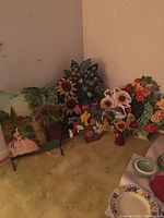 Image shows seven decorative floral stands arranged on floor against wall to showcase various sizes and detailed painted designs