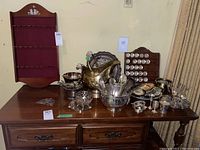 Overall shot of lot on table showing wooden rack at back and silver-plated pieces arranged in front