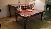 Wide view showing two tables, a coffee table in front and an end table behind, with decorative lamps on top and cords draped around