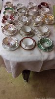 18 assorted teacups and saucers arranged in rows on a table