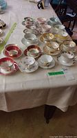 Overview of 17 bone china tea cup and saucer sets on table