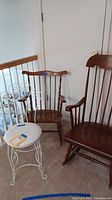 Three chairs shown: two wooden spindle rocking chairs and one white cushioned vanity chair with metal frame.