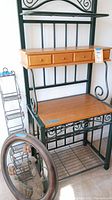 Full view of baker's rack showing wooden drawers and metal frame with wine rack storage below.