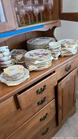 Full set displayed on wooden cabinet showing stacks of plates and cups